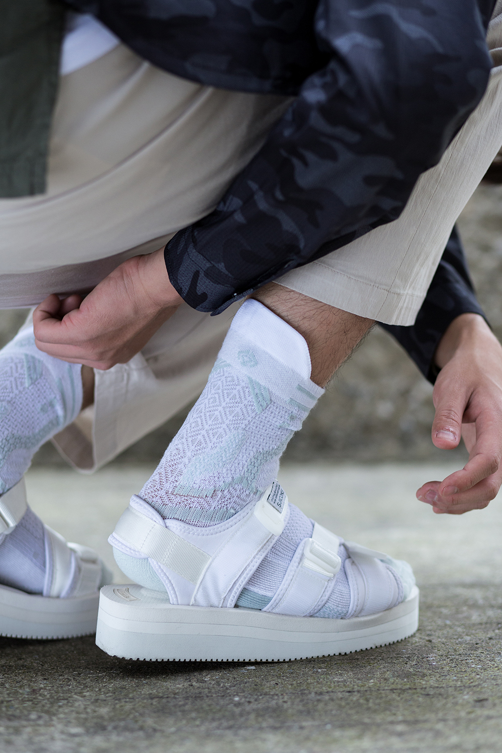 機能襪履設計品牌 nozzle quiz 經典"STREET AGILITY" 系列 lookbook，清爽中帶著日系休閒個性的迷彩紋外套，搭配suicoke的白色涼鞋與純白網眼編織長襪。細節佐以加長尼龍腰帶作為一點調皮地展現。