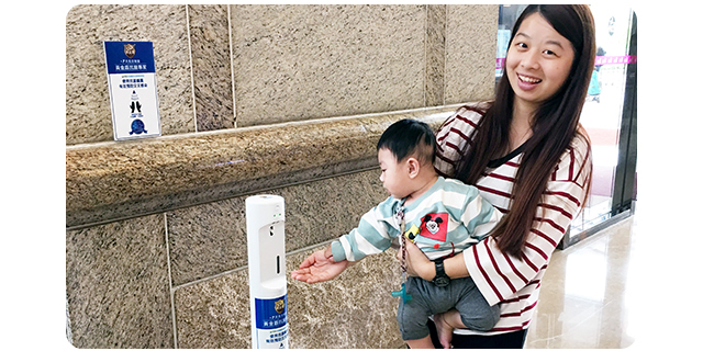 一位媽媽手裡抱者孩子，孩子手伸過去使用黃金盾抗菌清潔噴劑