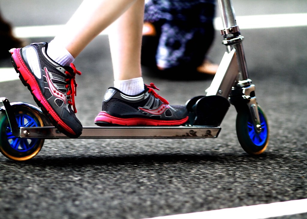 一個人穿著紅色的鞋子騎著鋁合金的電動滑板車