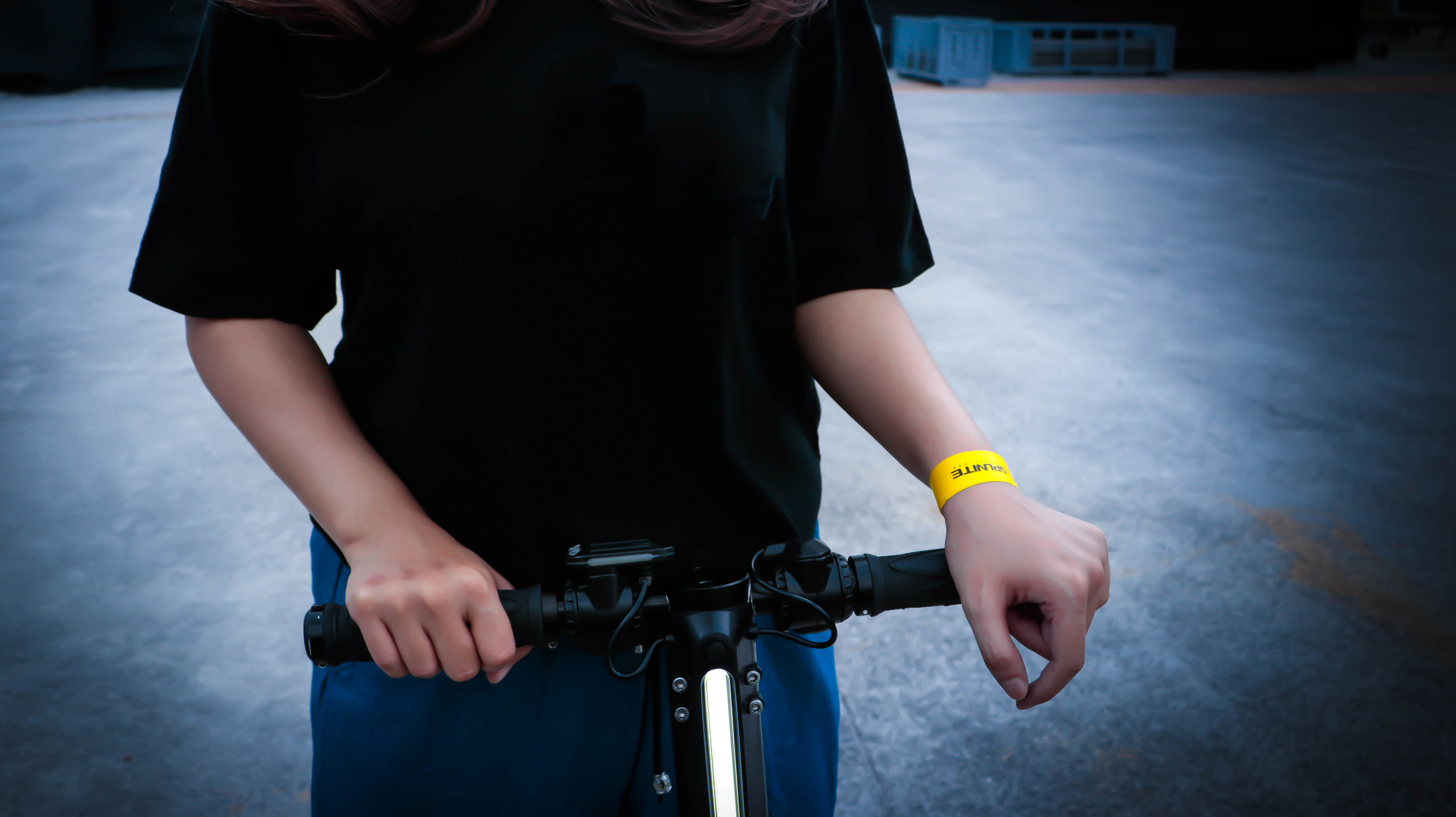 一個人穿著黑色衣服把兩隻手放在電動滑板車上