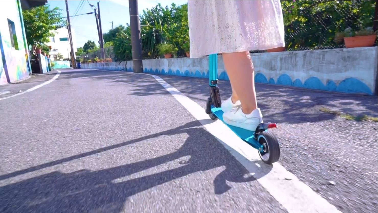 一個女孩騎著藍色的X5鋁合金電動滑板車在路上騎乘