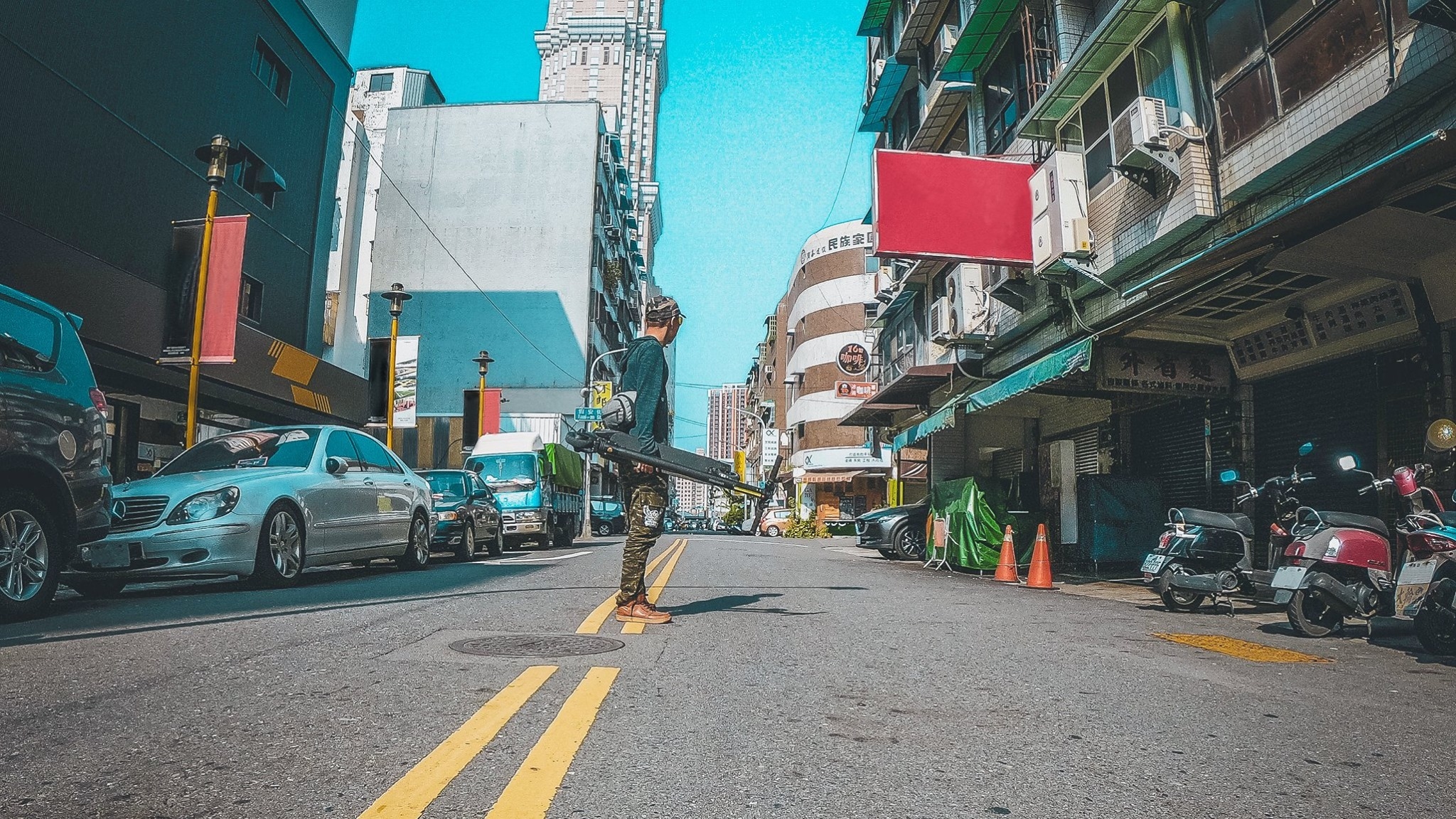 一個男生在路上拿著電動滑板車
