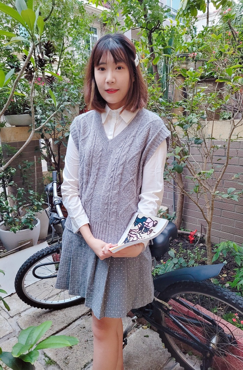 模特兒示範V領淺灰色針織背心穿搭，內搭白色襯衫呈現學院風