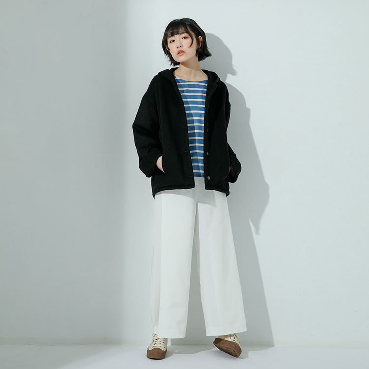 女模特兒身穿黑色連帽羊毛毛呢外套和白色打折造型長褲