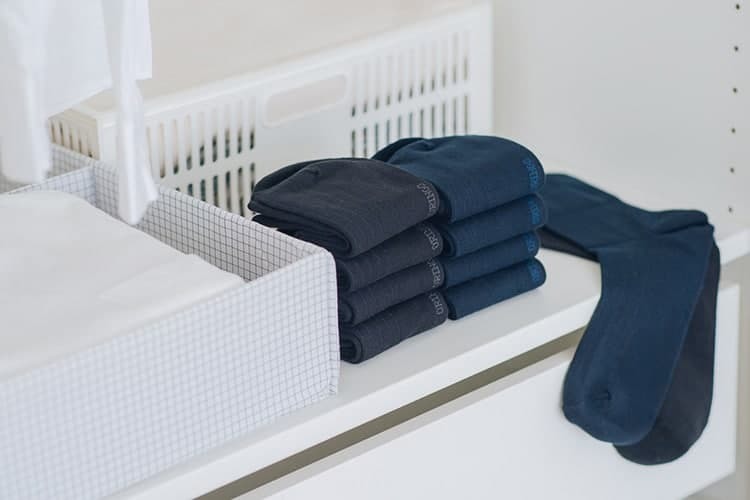  黑色與深藍色的無束縛紳士襪摺疊擺放在白色的衣櫃內
