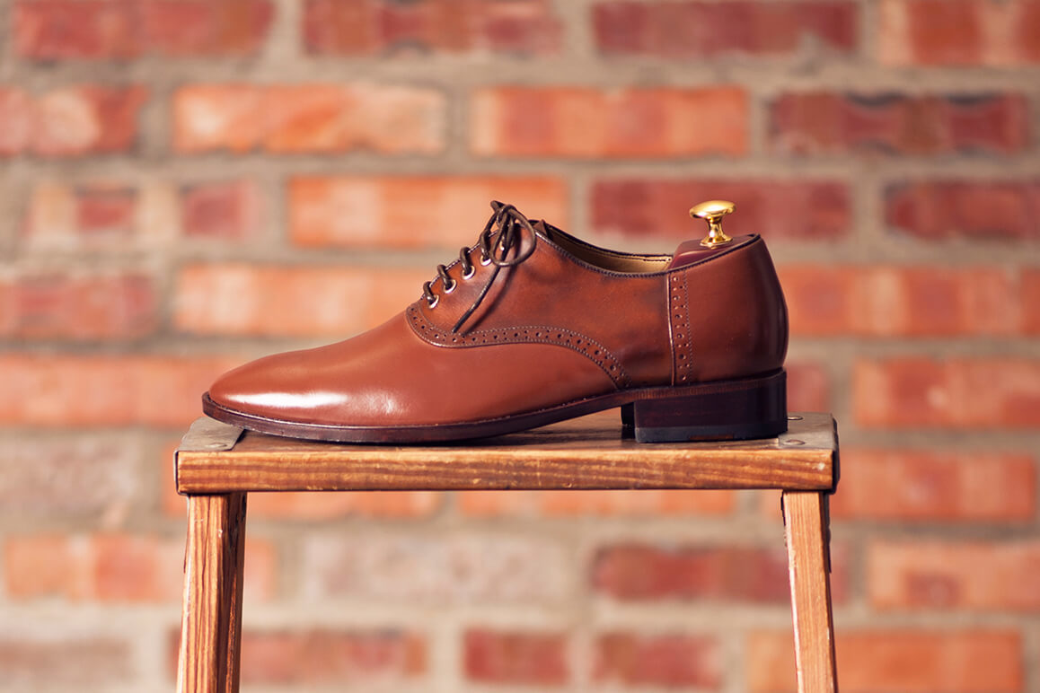 單只左腳咖啡色鞍部牛津鞋放在木椅上