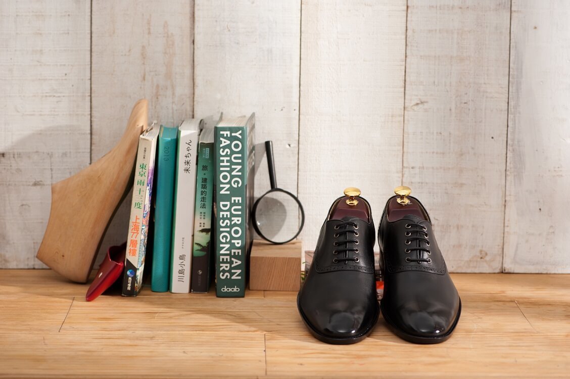 一雙黑色的鞍部牛津鞋與書本一起放在桌面上