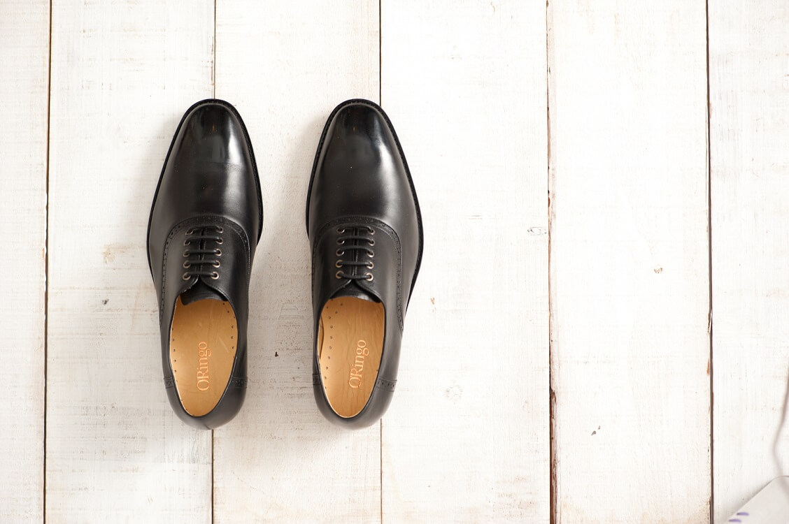俯視一雙在白木板上的黑色鞍部牛津鞋
