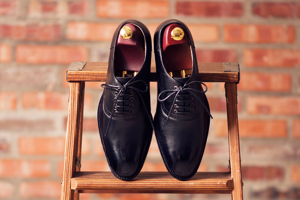 牛津鞋 一雙黑色鞍部牛津鞋正面架在木椅上