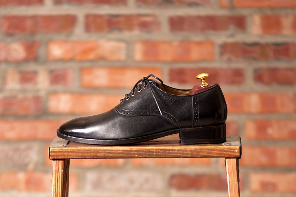 牛津鞋 單只左腳黑色鞍部牛津鞋放在木椅上