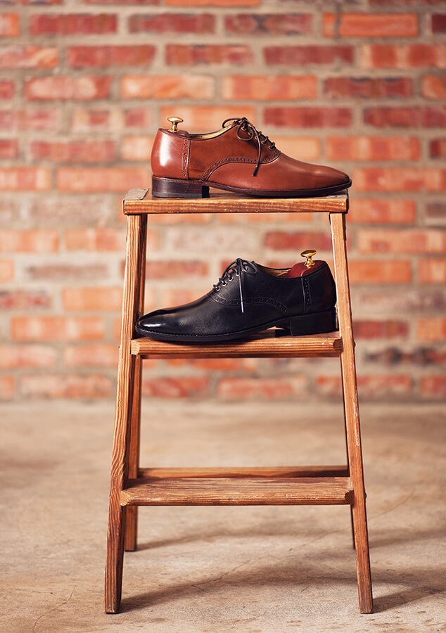 牛津鞋 黑色和咖啡色鞍部牛津鞋放在不同層的木梯上