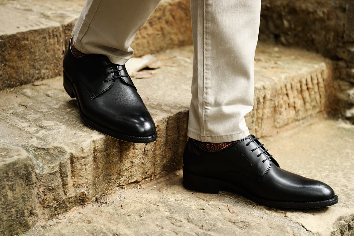 腳部特寫穿著卡其褲搭配黑色德比鞋的模特兒走下褐色石階