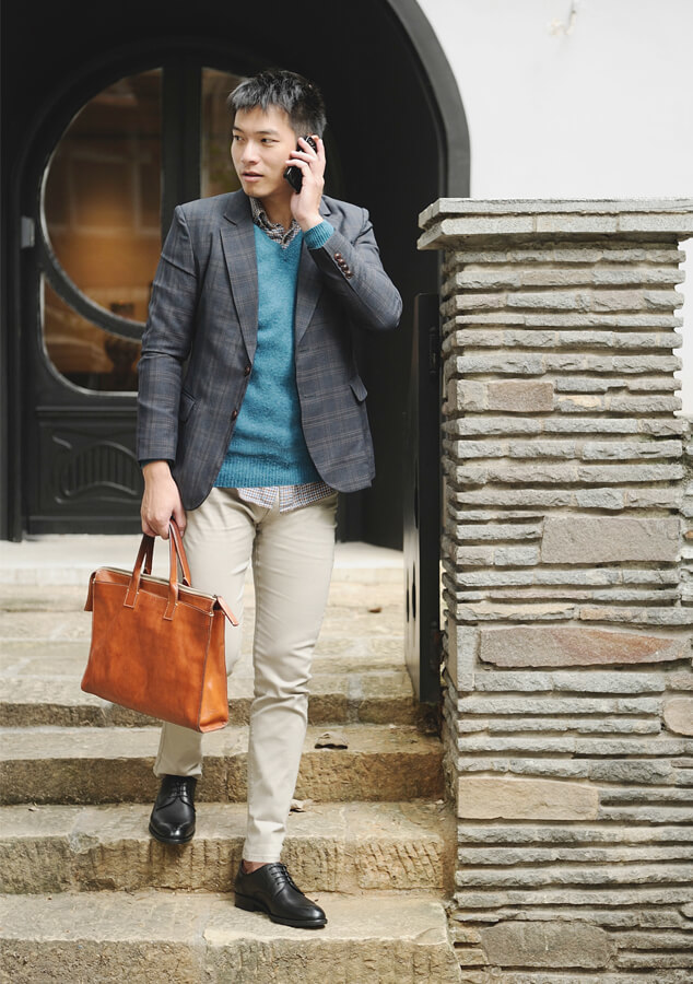 身穿灰色西裝外套搭配卡其褲與黑色德比鞋的模特兒走下石階