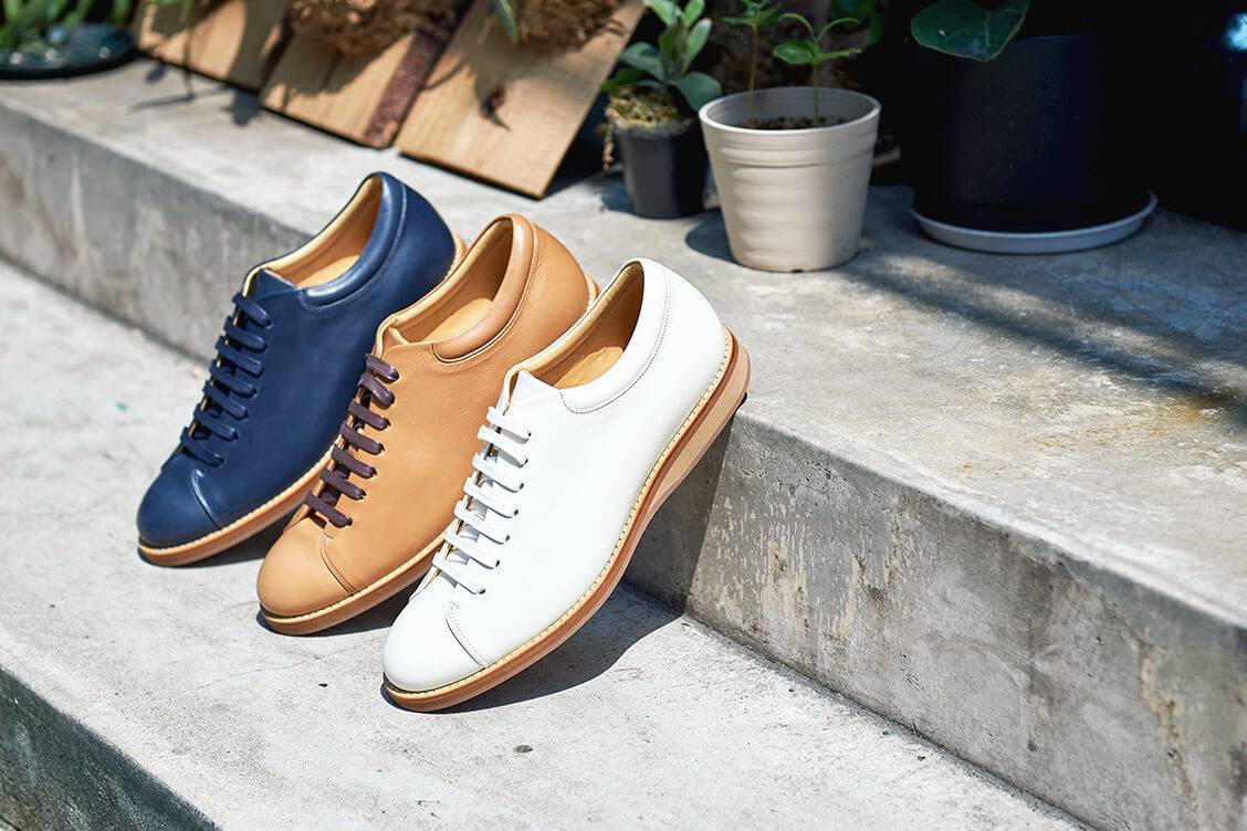 三只皮革休閒鞋白色闇夜藍色焦咖啡色面著陽光鞋跟架放在水泥樓梯台階上