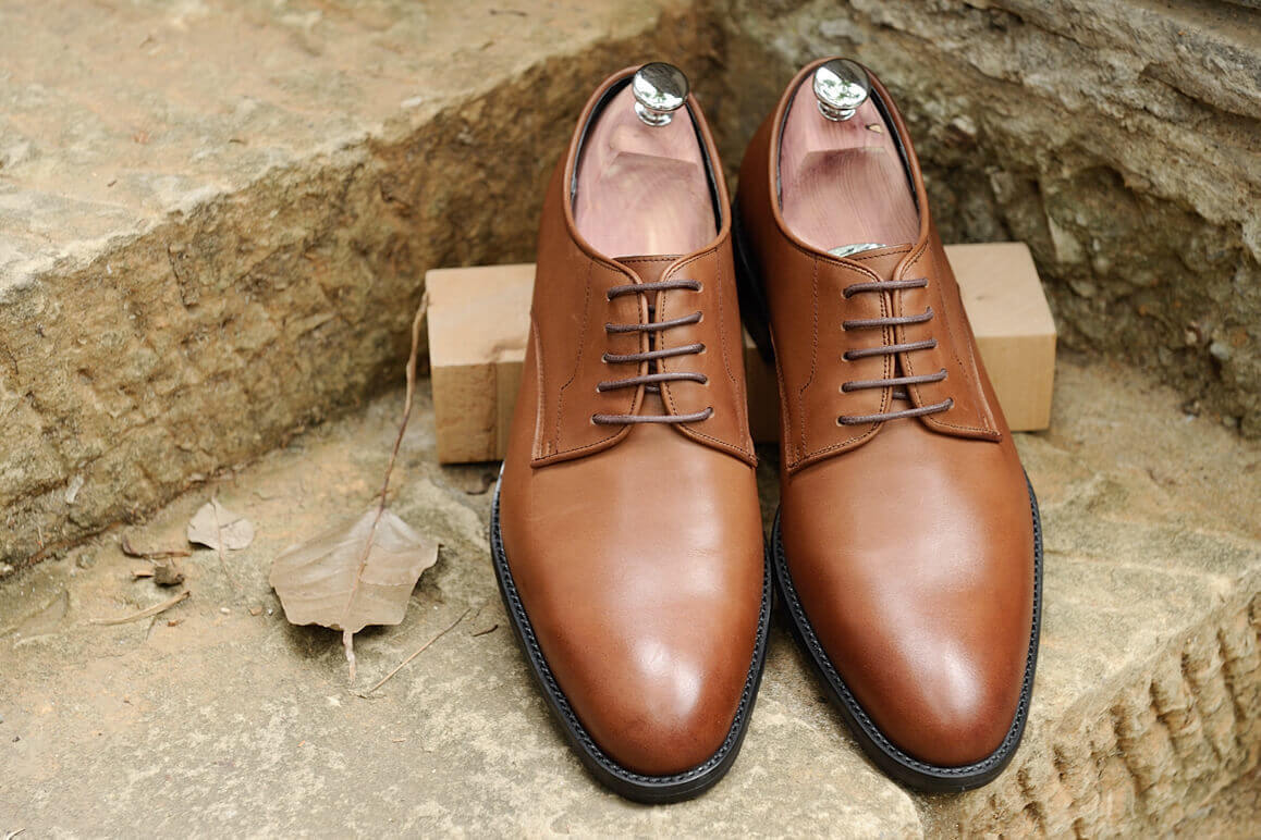 德比鞋 黃褐色的石階上擺放著一雙放有鞋撐的咖啡色德比鞋紳士鞋