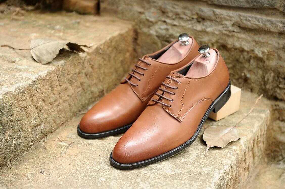 德比鞋 黃褐色的石階上擺放著一雙林果良品咖啡色德比鞋紳士鞋