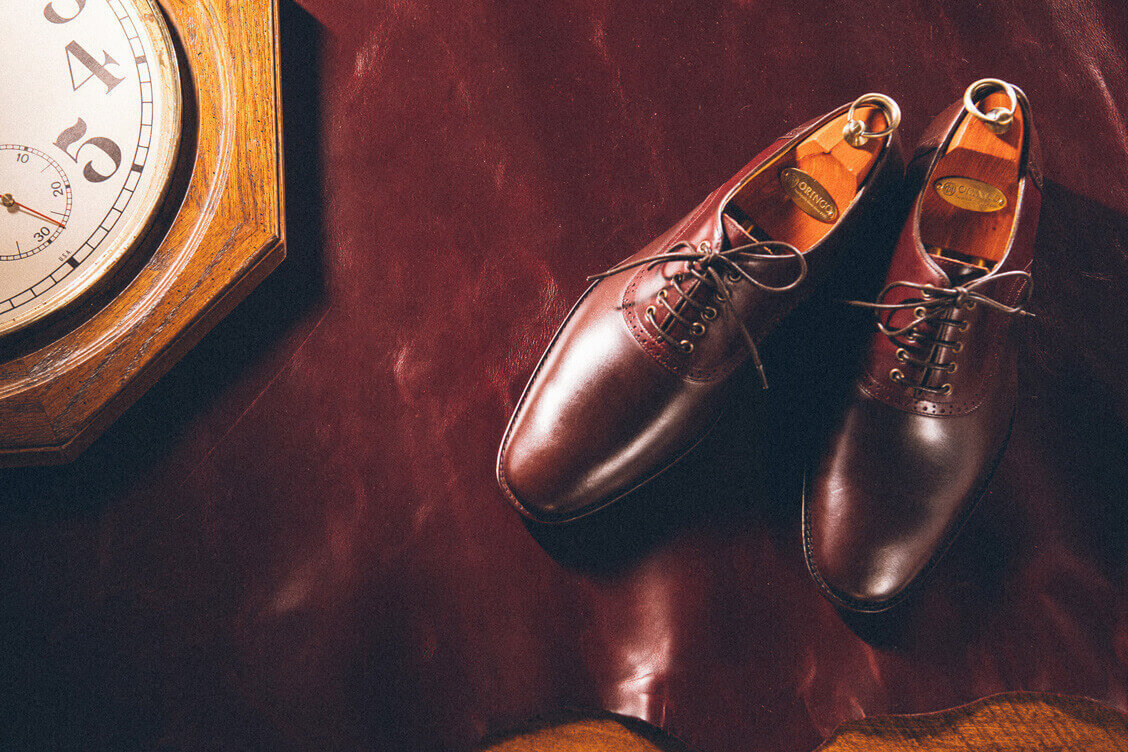 牛津鞋 雙配色鞍部牛津鞋與時鐘放在皮革上