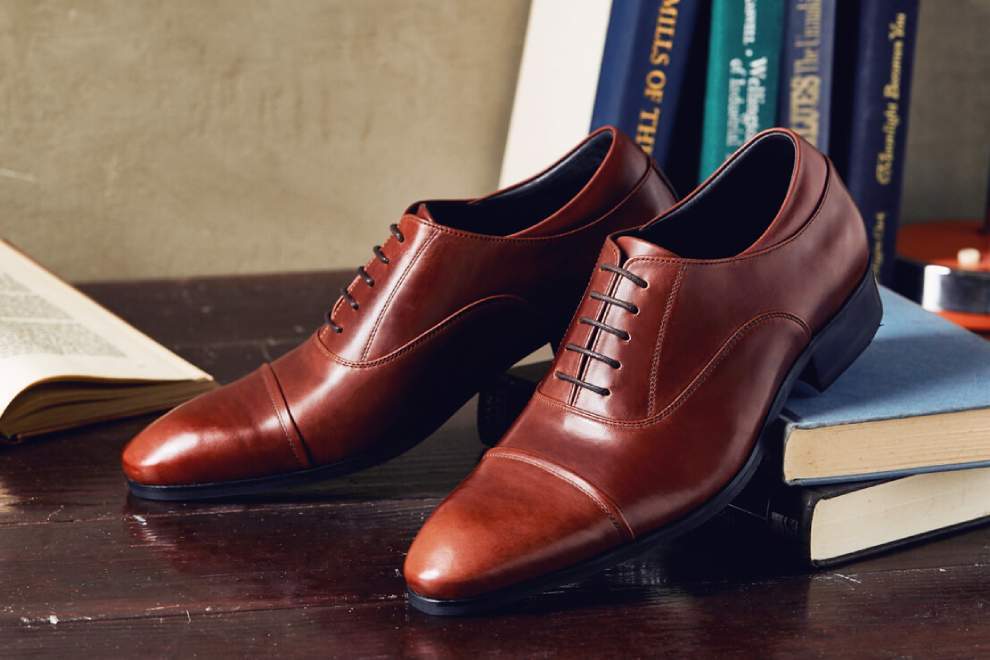 牛津鞋 一雙栗紅棕色基本款牛津鞋和書本擺在桌面上