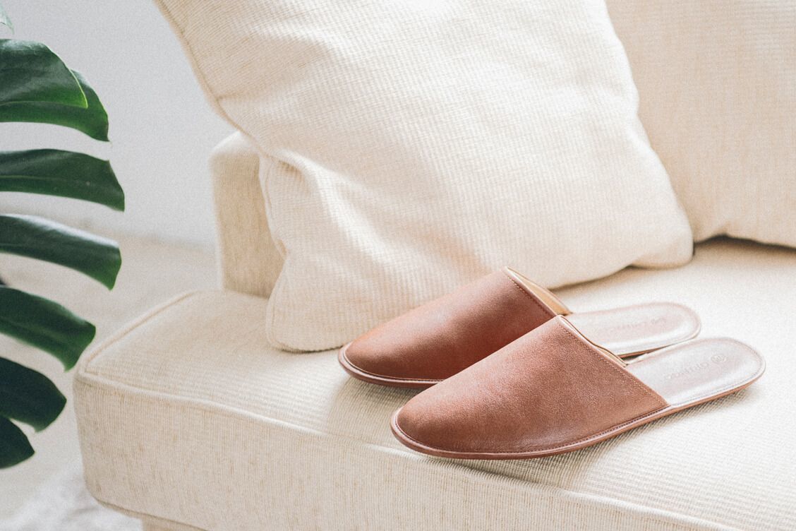 米白針織毯上放著一雙可可棕色的牛皮拖鞋