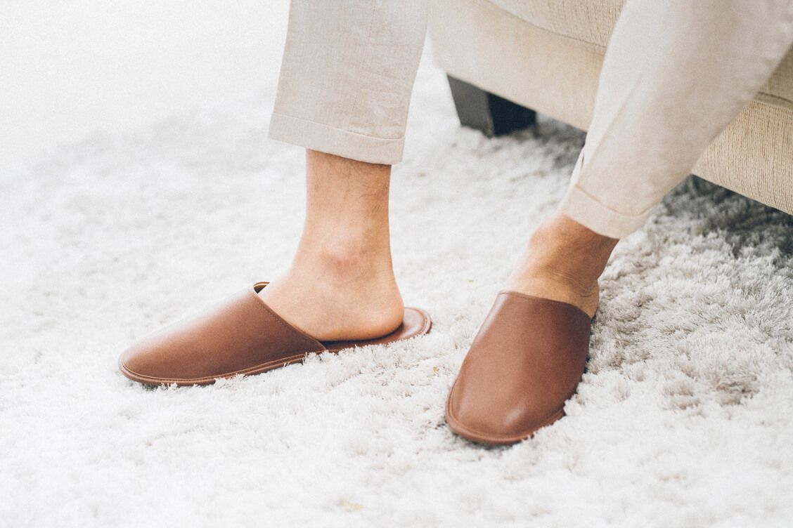 特寫模特兒腳部穿著亞麻褲與可可棕色的牛皮拖鞋