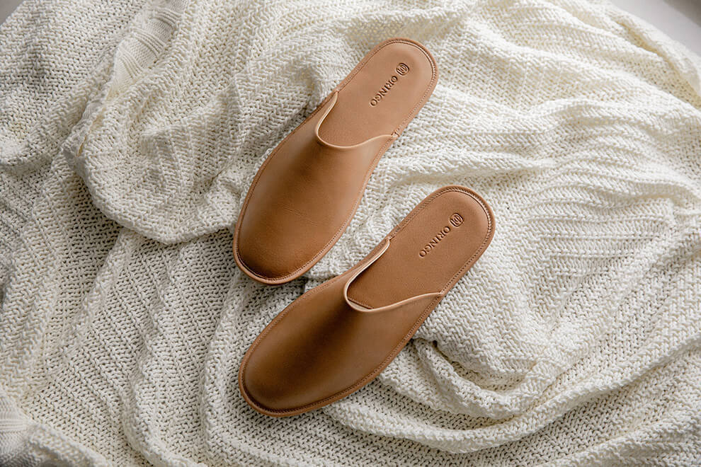 米白針織毯上放著一雙奶茶棕色的牛皮拖鞋
