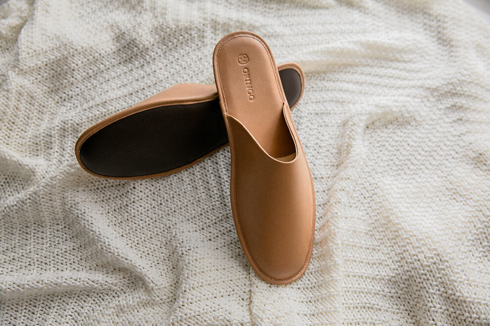 米白針織毯上擺著一正一反的奶茶棕色牛皮拖鞋