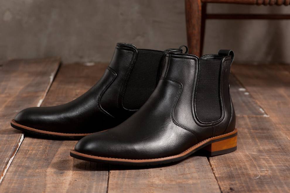 木板上擺著一雙黑色卻爾喜膠底靴