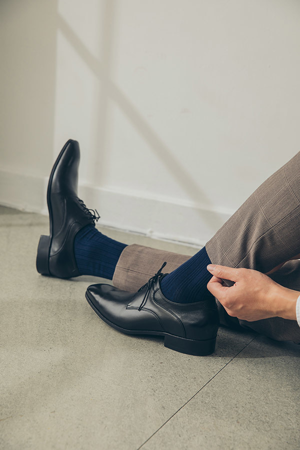 黑色流線德比鞋搭配灰棕色西褲與湛藍紳士襪