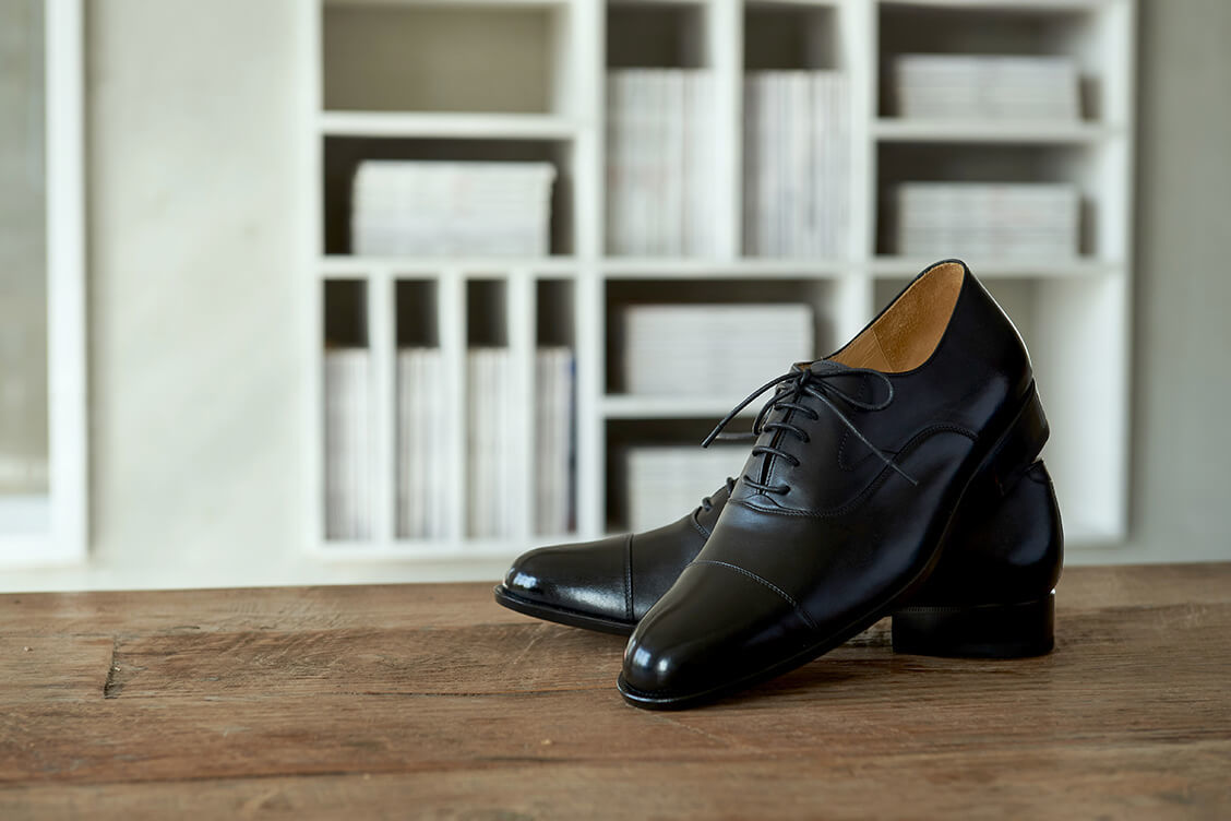 牛津鞋 一雙黑色鵝頸橫飾牛津鞋的交叉擺放在木桌上