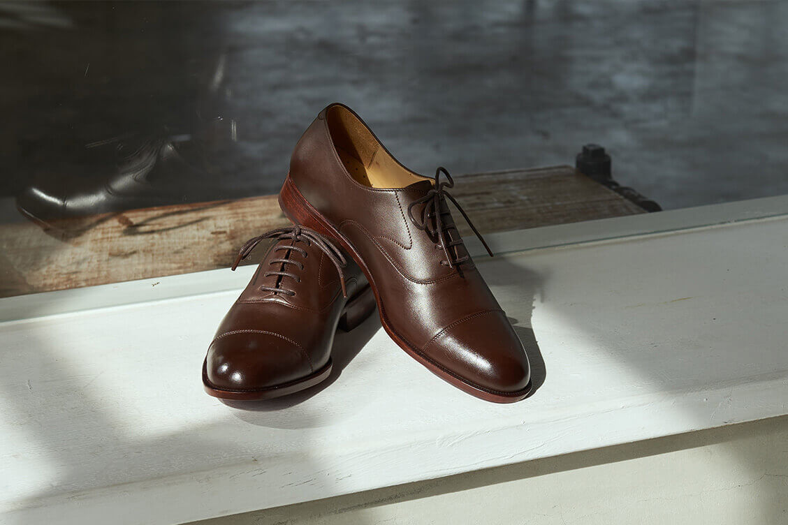 牛津鞋 白色窗台上擺著一雙咖啡色的牛津鞋