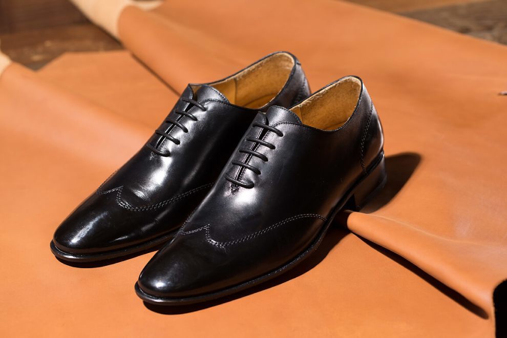 牛津鞋 一雙黑色翼紋縫線牛津鞋展示於褐色皮革上