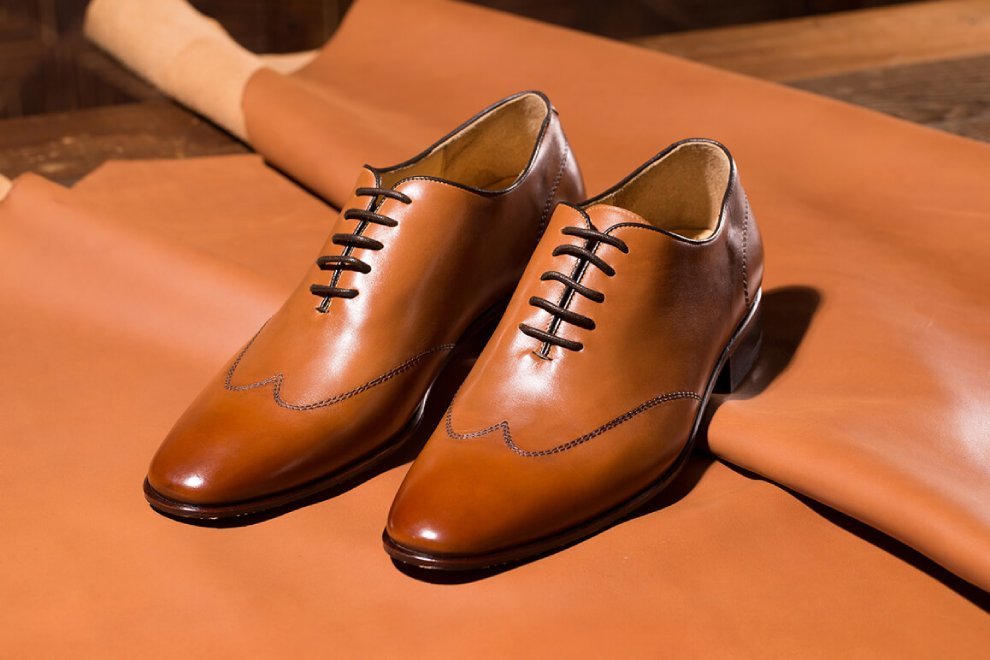 一雙蜜棕色翼紋縫線牛津鞋展示於褐色皮革上
