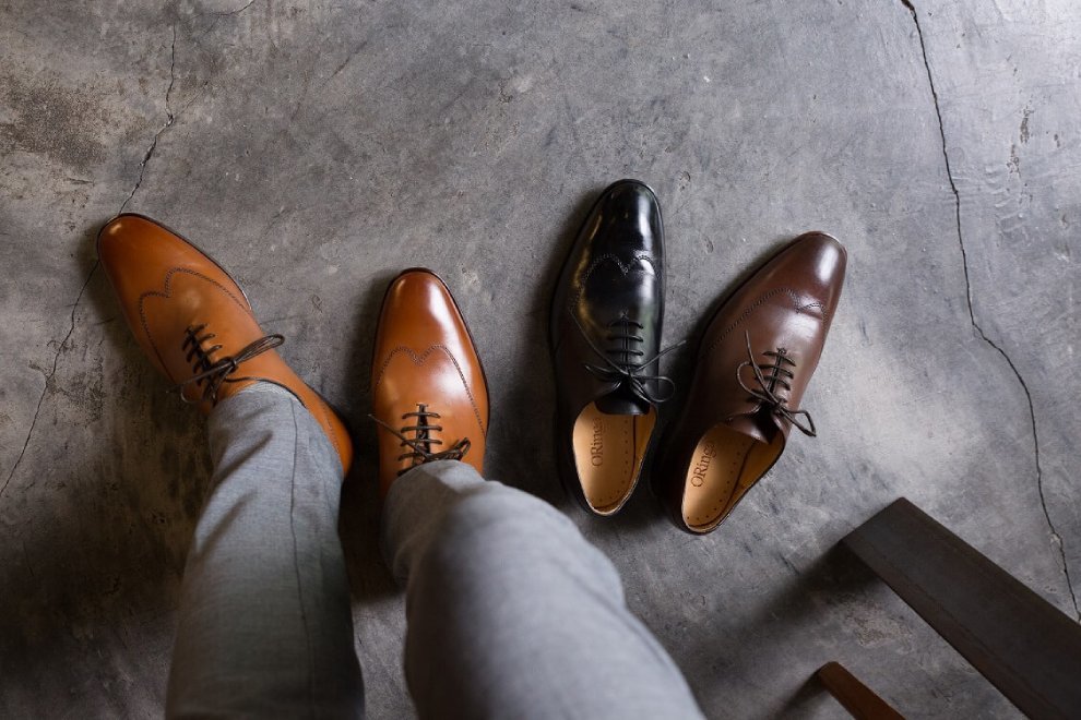 特寫灰色西裝褲搭配蜜棕色翼紋牛津鞋與單只黑色和咖啡色牛津鞋