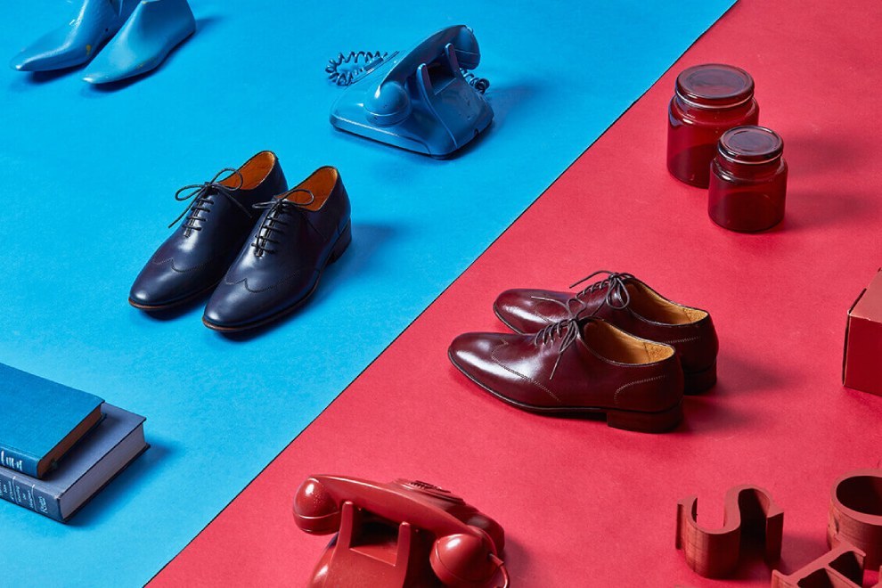 酒紅色與藏青色的油感皮革牛津鞋擺放在紅藍色分割的色板上