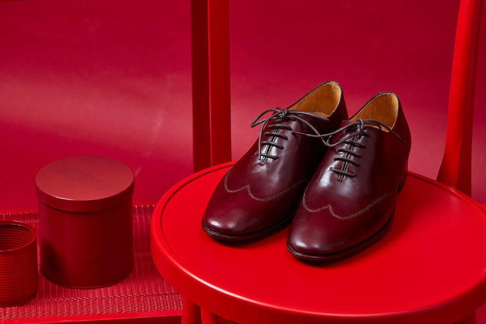 一雙酒紅色的油感皮料的牛津鞋擺放紅色鐵椅上