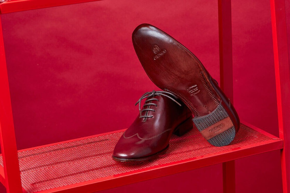 在紅色鐵架上展示酒紅色牛津鞋皮革鞋大底