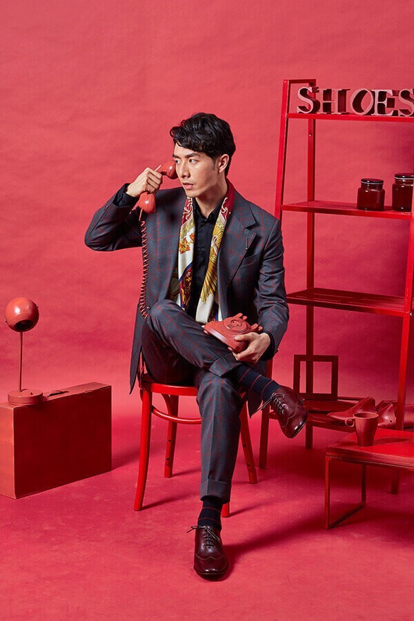 坐姿模特穿著深色格紋西裝搭配酒紅色全裁片皮底牛津鞋