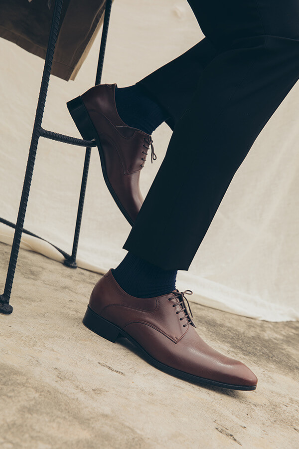 展示可可咖啡色經典流線德比鞋搭配黑西裝褲與黑紳士襪