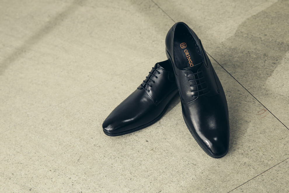 展示黑色經典流線德比鞋牛皮皮料在光線下的皮革光澤