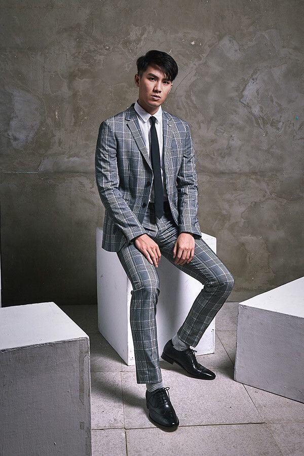 牛津鞋 坐姿模特身穿灰色商務格紋西裝搭配黑色3/4雕花鋸齒翼紋牛津鞋