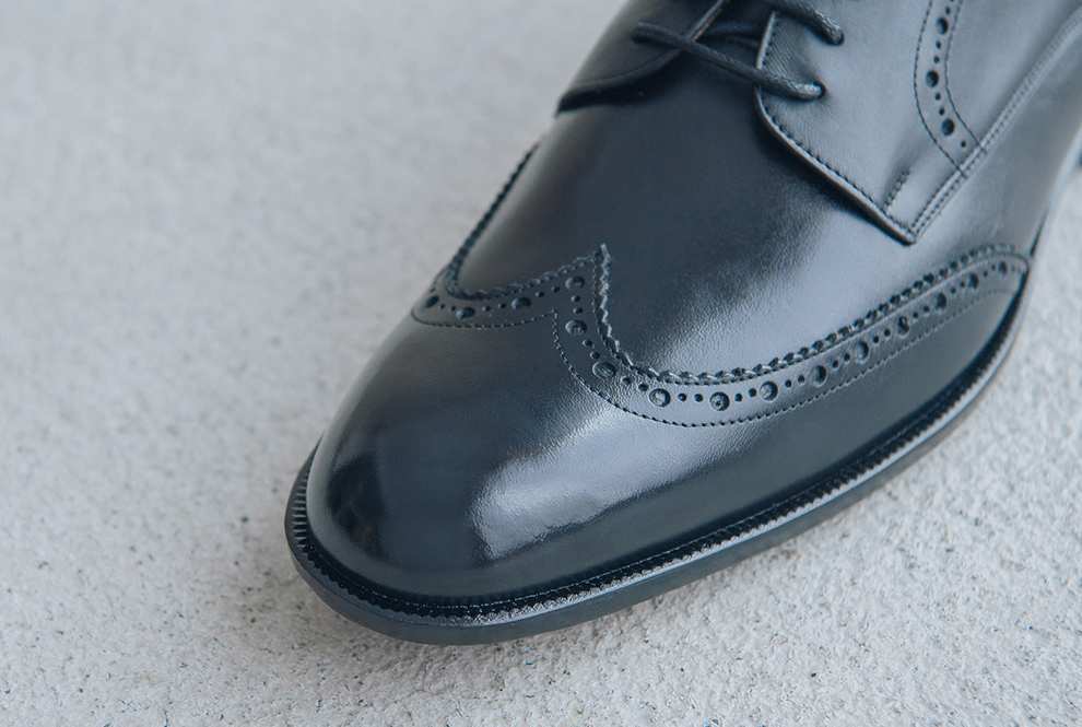 特寫經典黑色的翼紋雕花德比鞋鞋面翼紋的鋸齒邊飾與手工雕孔