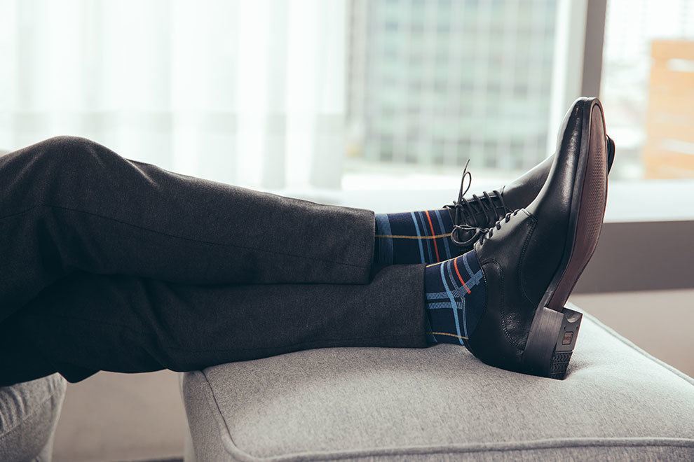 特寫淺藍色格紋抗菌除臭紳士襪搭配深灰西裝褲與黑色德比鞋