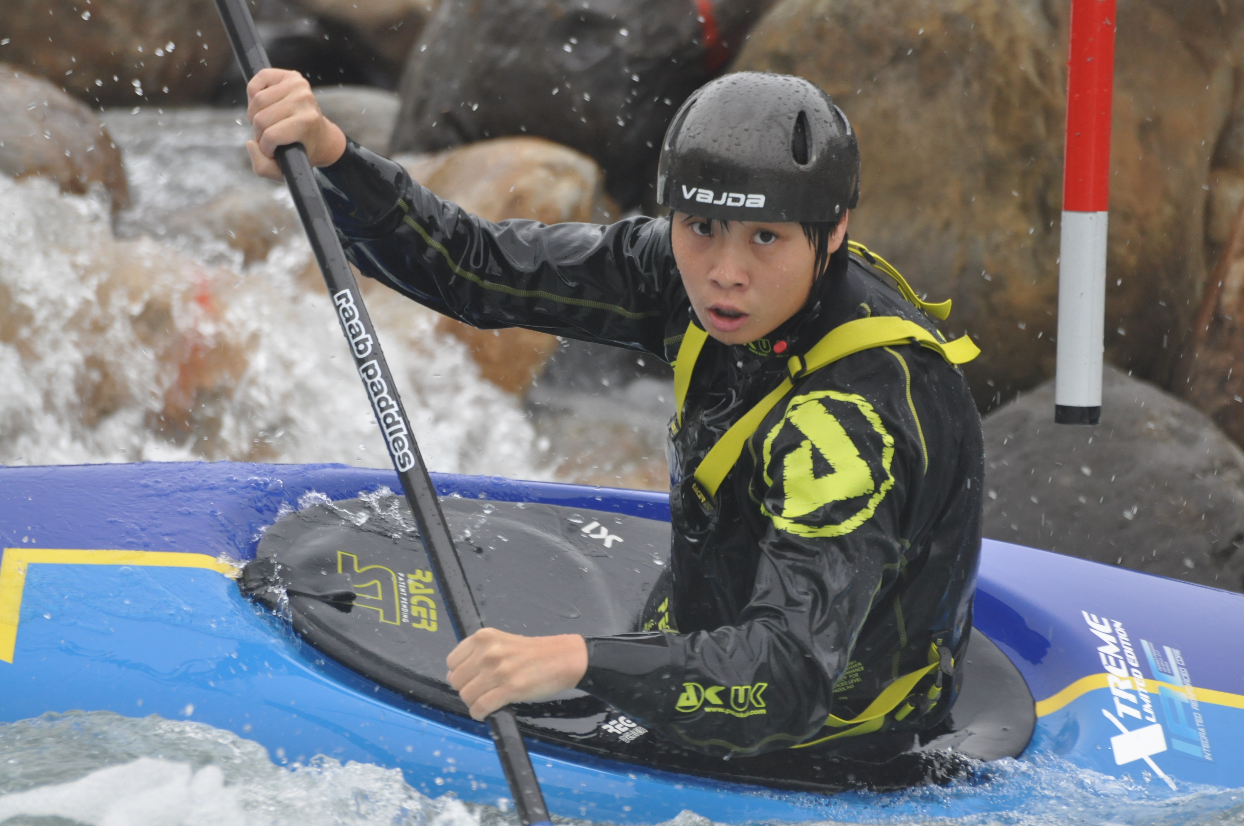 張竹涵正在藍色的輕艇中，兩手握著船槳，頭戴著黑色頭盔眼睛盯著前方的標竿。