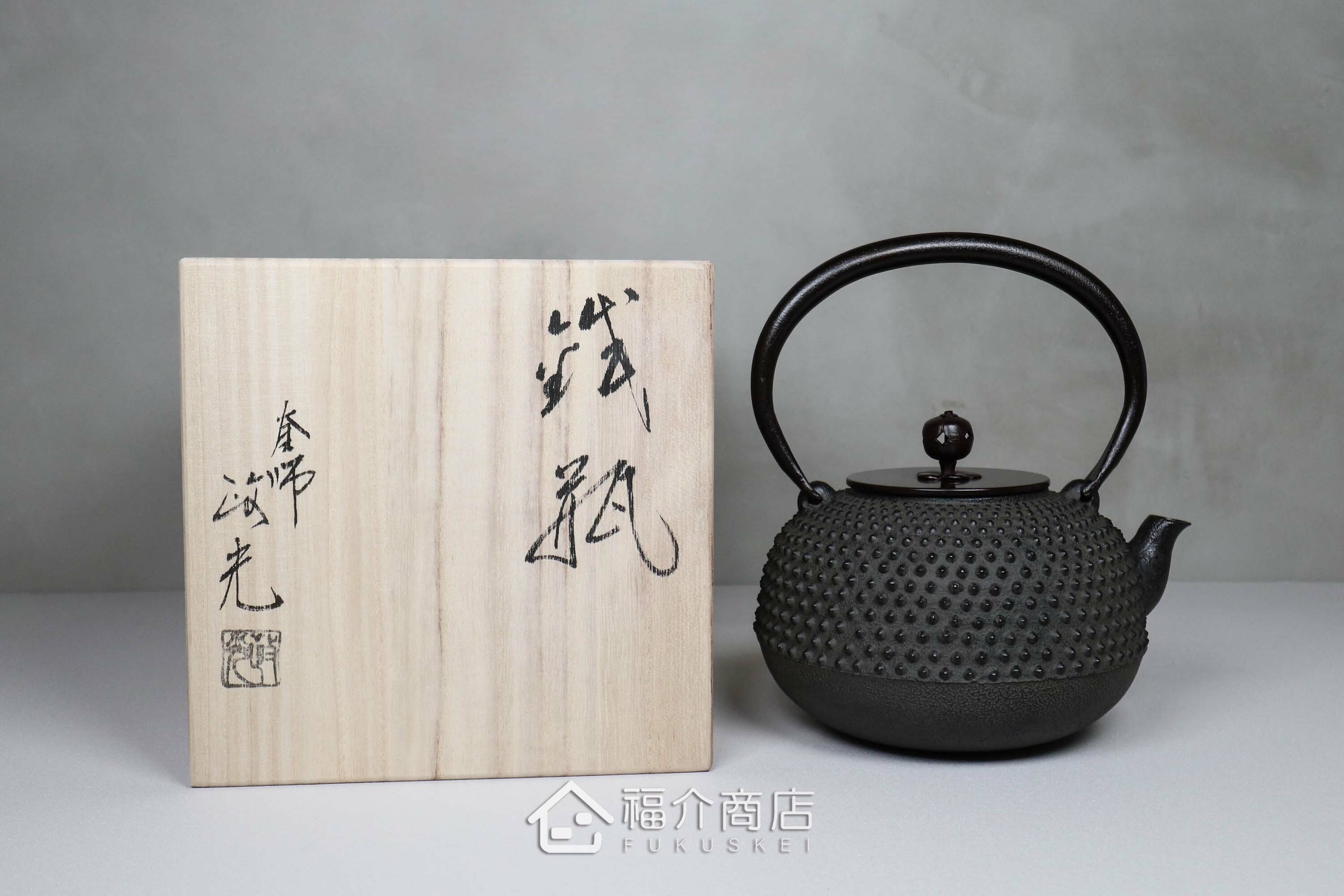 黑色鐵壺旁為木箱包裝