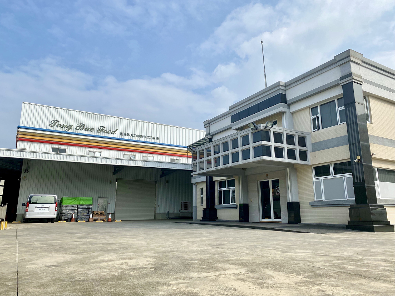 統百食品的辦公大樓與工廠，旁邊停有送貨車及用帆布覆蓋的棧板