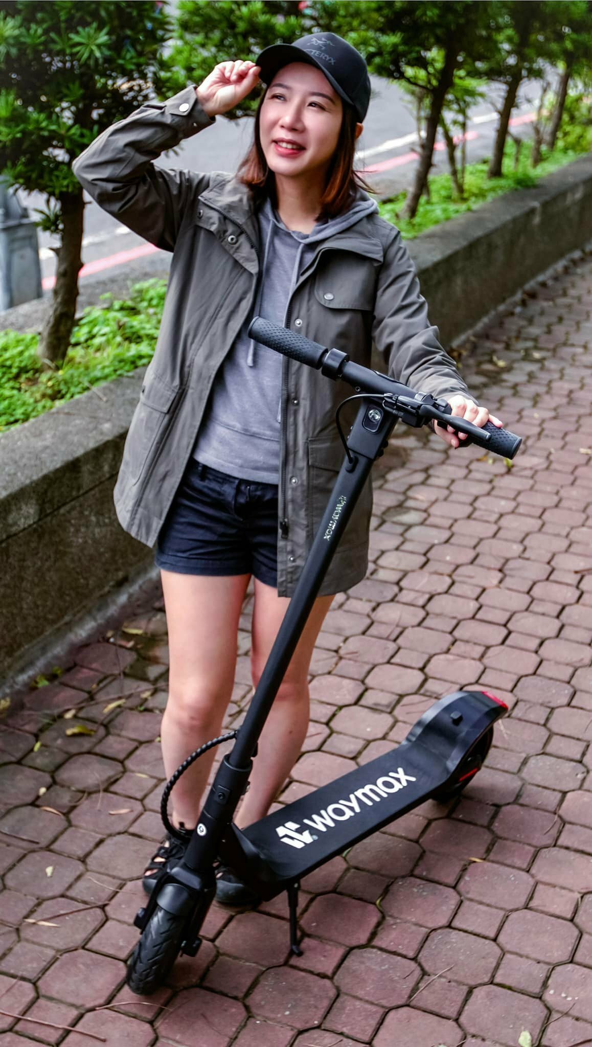 一位女生站在黑色的Waymax X7電動滑板車旁邊