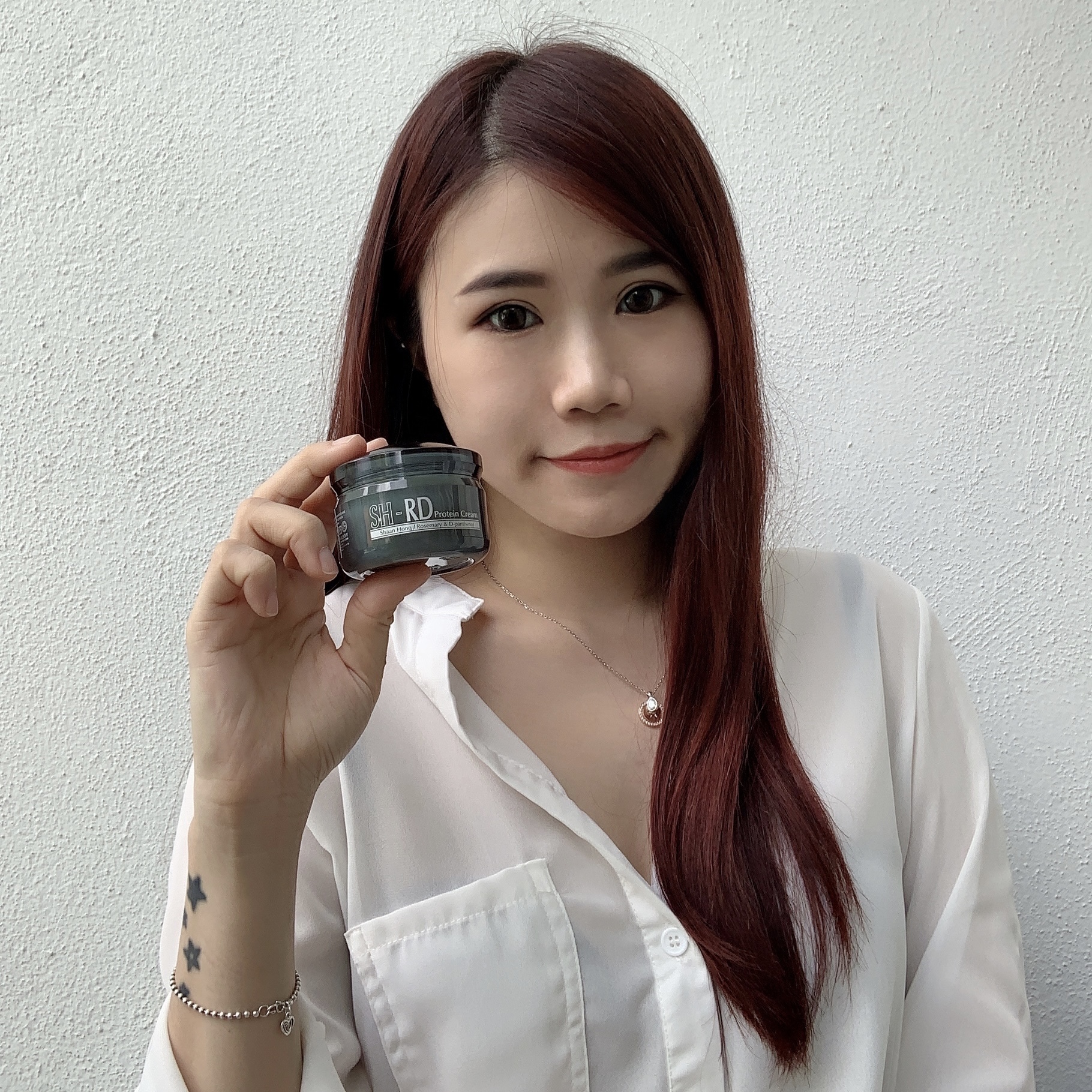 马来西亚红色头发的网红手中那这一罐SH-RD绿色瓶身的护发霜