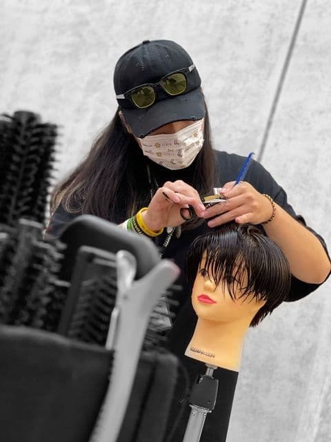 美髮設計師Rebels正利用假人頭練習剪髮技術