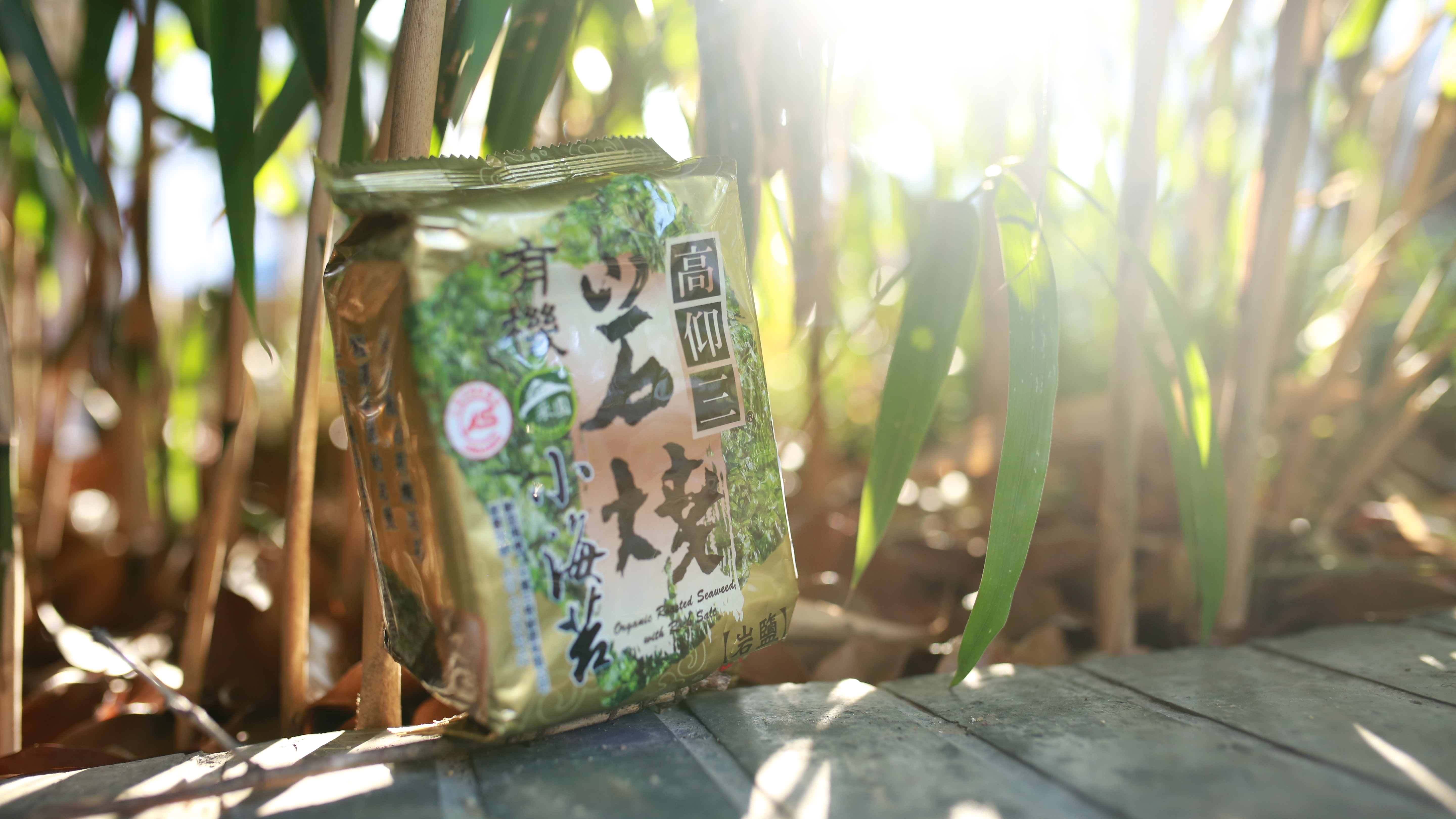 一包高仰三有機岩燒小海苔在小竹林地木頭小徑之上，佈滿陽光。