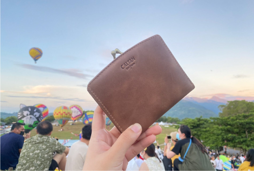 手裡拿著有口金的褐色中夾，背景裡有熱氣球，客人好評